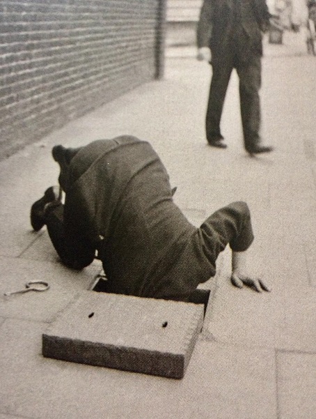 Man Looking inside a sidewalk inspection door